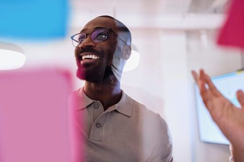 Portrait of a black man presenting his ideas on a glass wall during a business meeting