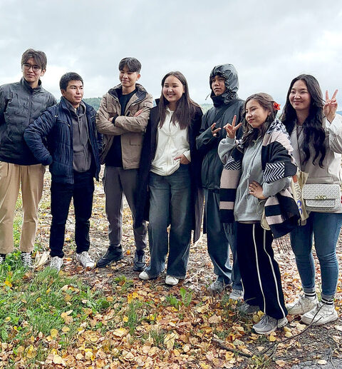 Eine Gruppe von männlichen und weiblichen Jugendlichen, bekleidet mit Regenjacken, posiert lächelnd für die Kamera.