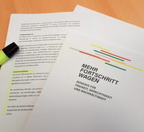 Auf einem Tisch liegt der Koalitionsvertrag "Mehr Fortschritt wagen" von SPD, Bündnis 90/ Die Grünen und FDP. Mit einem gelben Marker ist der Abschnitt "Erwachsenenbildung" gelb hervorgehoben.