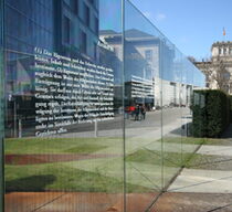 Glasinstallation mit eingravierten Artikeln des Grundgesetzes vor Jakob-Kaiser-Haus in Berlin, im Hintergrund das Reichstagsgebäude
