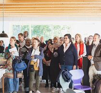 Eine Gruppen vieler Menschen steht zusammen in einem großen Raum.