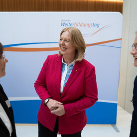 Drei Frauen stehen vor einer Fotowand und lachen gemeinsam.