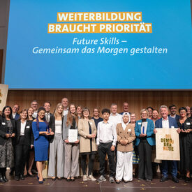 Eine große Gruppe von Männern und Frauen steht auf einer Bühne.