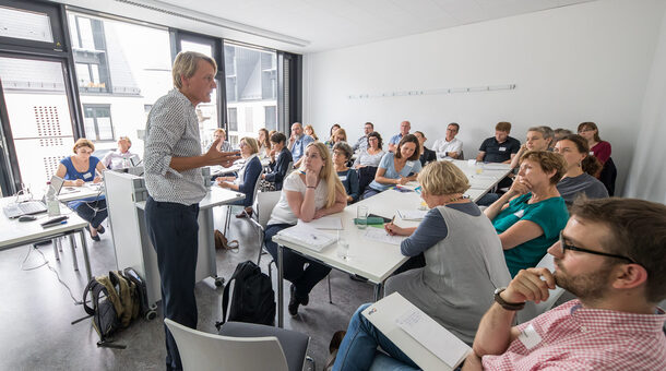 Referent spricht zu Gruppe im Kursraum.