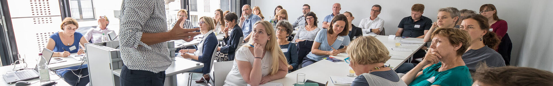 Referent spricht zu Gruppe im Kursraum.