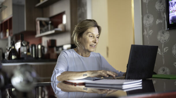 Ältere Dame arbeitet zu Hause am Laptop