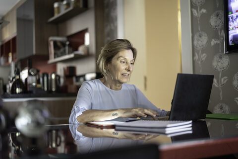 Ältere Dame arbeitet zu Hause am Laptop