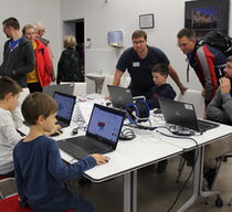 Männer und Jungs sitzen vor Laptops