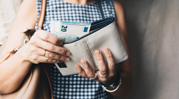 Eine Frau zieht einige Geldscheine aus ihrer Geldbörse