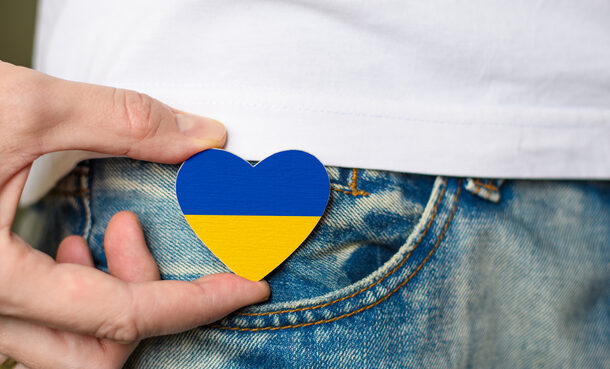 Mann hält ein Herz aus Holz in den Farben der Ukraine (blau und gelb) zwischen zwei Fingernoliday of Ukraine