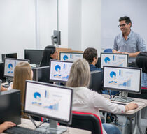 Ein Lehrer unterrichtet Erwachsenen in einem Computerkurs