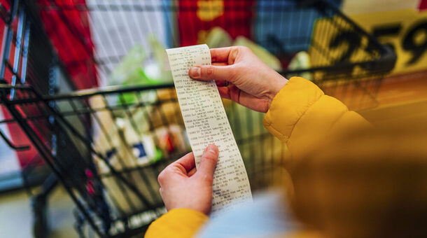 Eine Kundin prüft im Supermarkt nach dem Wareneinkauf ihren Kassenzettel