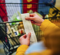 Eine Kundin prüft im Supermarkt nach dem Wareneinkauf ihren Kassenzettel
