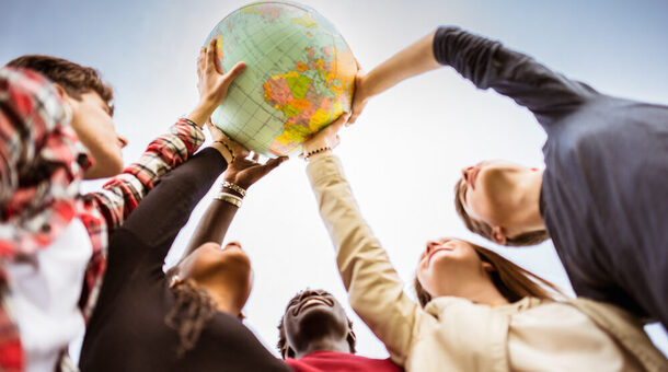 Jugendliche stellen im Kreis und halten gemeinsam einen Globus in die Höhe.