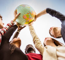 Jugendliche stellen im Kreis und halten gemeinsam einen Globus in die Höhe.