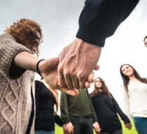 Junge Menschen stehen im Kreis und halten sich an den Händen
