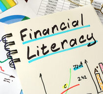 Auf einer Seite eines Notizbuches stehen die Worte "Financial Literacy". Daneben sowie auf weiteren Blättern sind bunte Tabellen, Grafiken und Zahlen zu sehen.