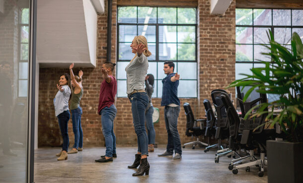 Mitarbeitende machen Fitnessübungen im Büro