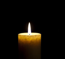 Eine einzelne Kerze brennt vor dunklem Hintergrund