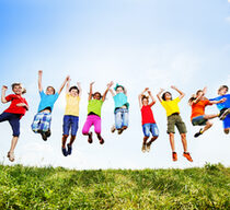 Eine Gruppe von Kindern in bunter Kleidung springt fröhlich in die Luft