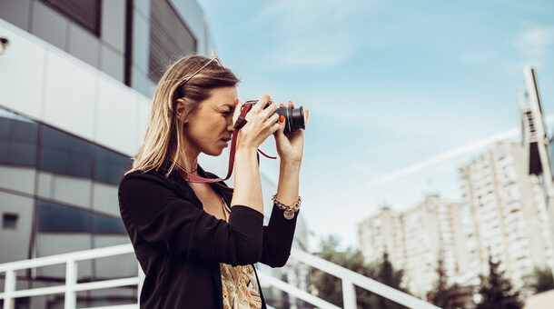 Eine Frau fotografiert mit einer Digitalkamera in einer Stadt