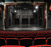 Blick auf einen leeren Theatersaal mit roten Sitzen sowie eine leere Bühne