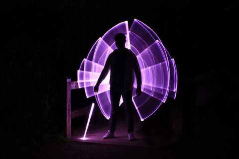 Silhouette eines Mannes, der mit einem Lichtschwert steht (Lightpainting-Fotografie)