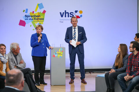 Angela Merkel und Moderator am Rednerpult