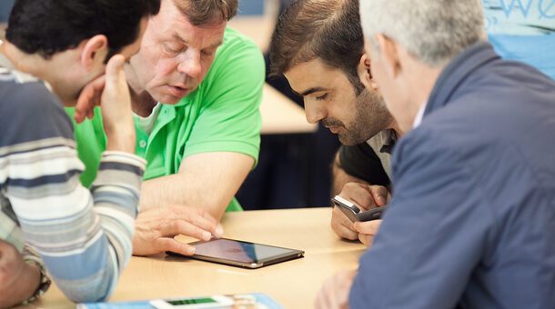 Lernende schauen gemeinsam auf ein Tablet.