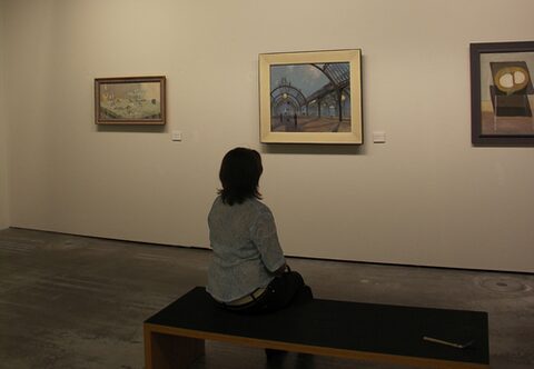 Besucherin betrachtet Gemälde im Museum.