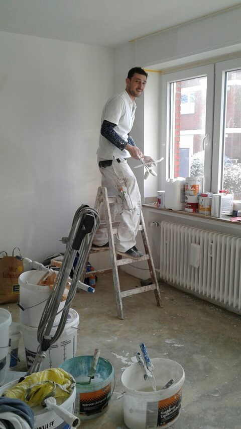 Junger Mann streicht Wände in Wohnung