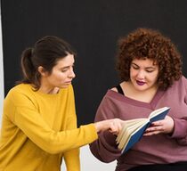 Eine Ehrenamtlerin hilft einer Frau beim Lesen lernen