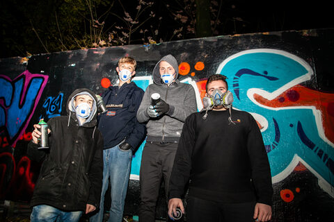 Teilnehmer der Hip-Hop-Werkstatt posieren vor der Graffiti-Wand.