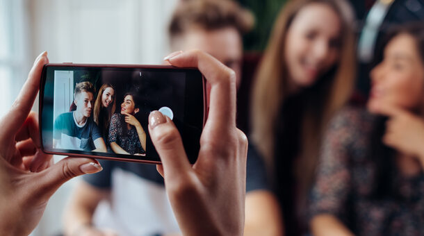 Frau macht mit Smartphone Foto von jungen Menschen