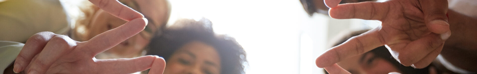 Junge Menschen bilden mit den Fingern Kreis aus Peace Zeichen.