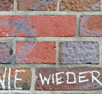 Symbolbild. Auf einer Ziegelsteinwand stehen die Worte "Nie wieder"