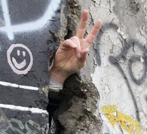Hand, die durch ein Loch in der Mauer gesteckt wurde und das Victory-Zeichen macht