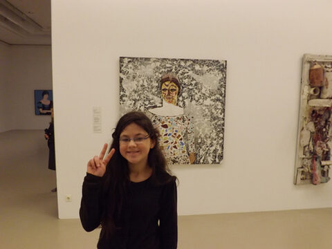 Mädchen posiert vor Gemälde im Museum