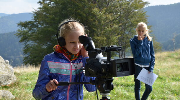 Mädchen filmt mit einer Kamera auf Stativ