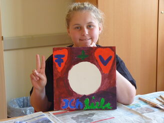 Mädchen zeigt selbstgemaltes Bild.