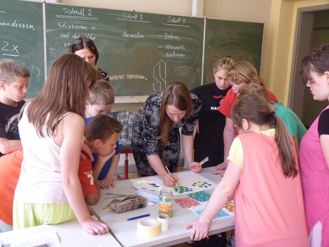 Kursleiterin erklärt den Kindern eine Maltechnik.