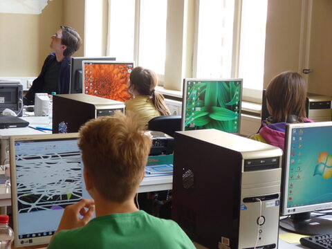 Kinder an PC Arbeitsplätzen schauen zur Kursleiterin