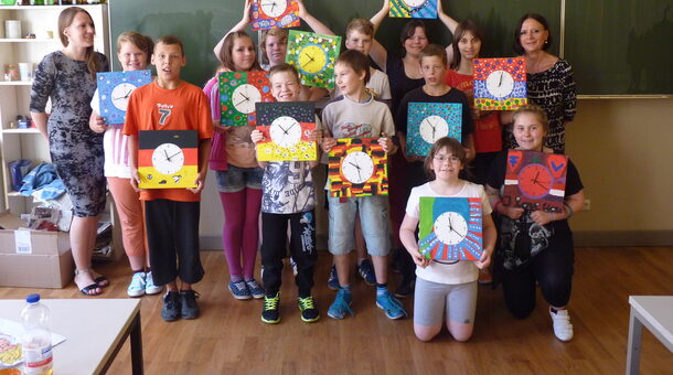 Gruppenbild: Die Kinder zeigen selbstgestaltete Wanduhren