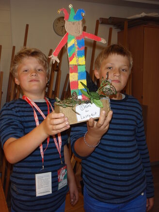 Zwei Jungen zeigen selbstgebastelte Pappfigur