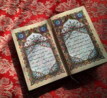 Ein aufgeklappter Koran mit arabischen Schriftzeichen und bunten Verzierungen