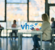 Blick durch eine Scheibe in einen vhs-Schulungsraum mit Teilnehmenden