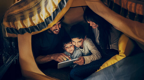 Ein Mann, einen Frau und zwei kleine Kinder lesen gemeinsam unter einer Decke.