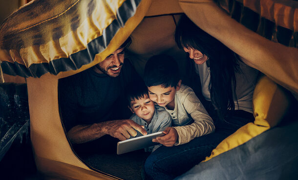 Ein Mann, einen Frau und zwei kleine Kinder lesen gemeinsam unter einer Decke.