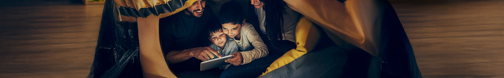 Ein Mann, einen Frau und zwei kleine Kinder lesen gemeinsam unter einer Decke.