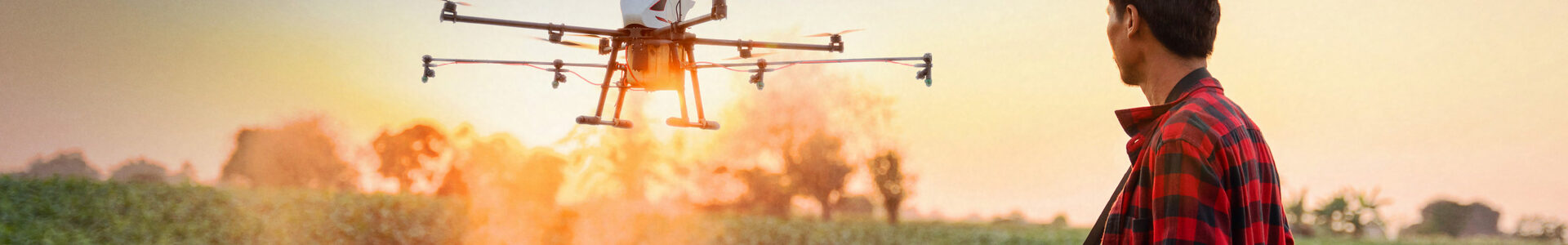 Ein Mann steht auf einem Feld und steuert eine landwirtschaftliche Drohne.